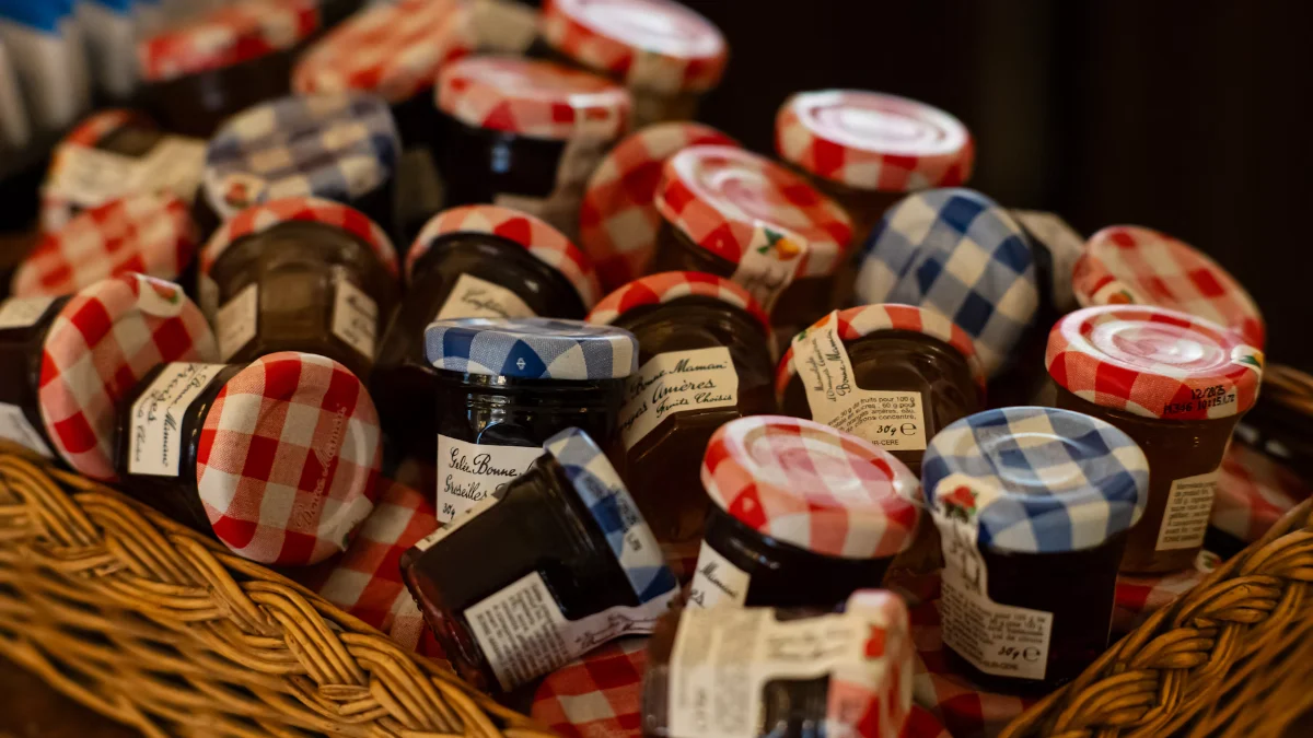 A basket of small jam jars with checked lids
