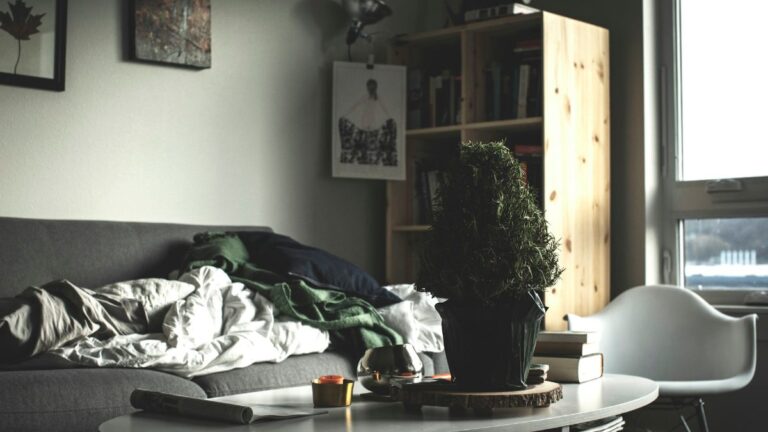 Clothes piled on a sofa in a dimly lit living room