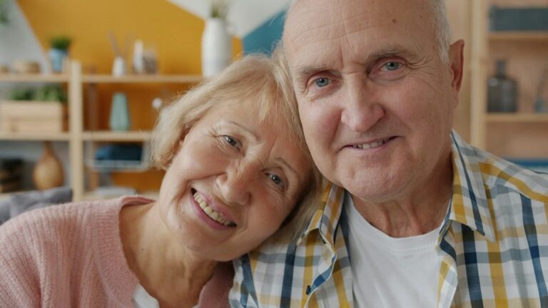 Smiling elderly couple posing cheek to cheek at home