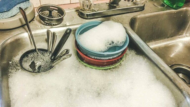 Dirty dishes and cutlery soaking in a soapy kitchen sink