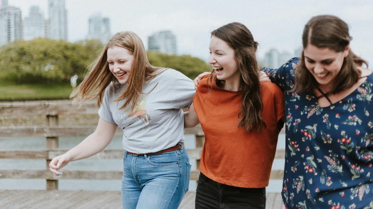 Three friends laughing together while walking outdoors