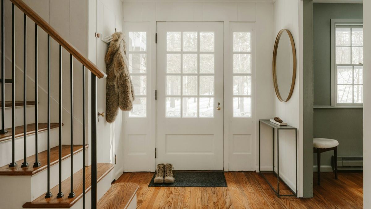 Bright home entryway with wooden stairs and a glass front door