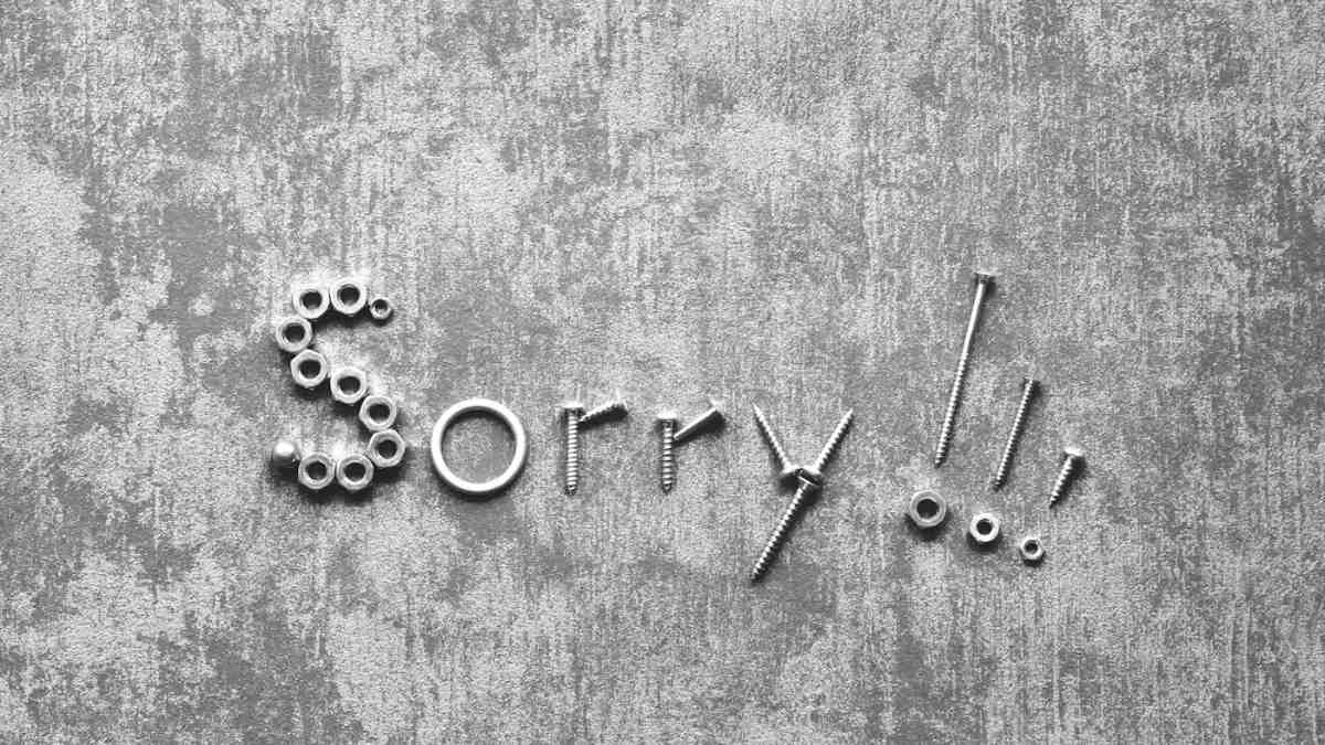 The word sorry spelled out in metal letters on a grey concrete wall