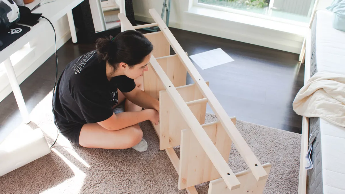 A woman assembling a wooden shelving unit at home