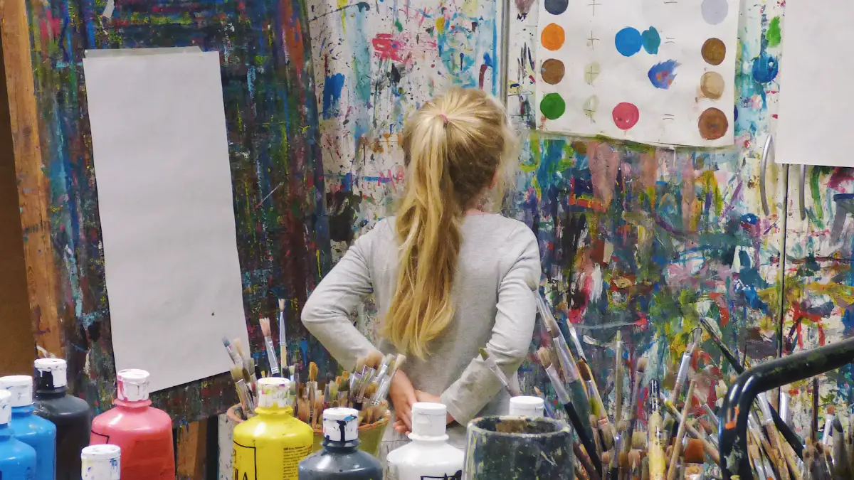 A child painting in an art studio surrounded by paint pots