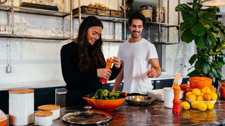 A man and woman cooking together at a kitchen table