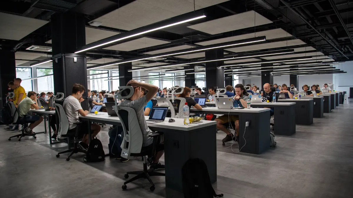 A large open-plan office full of people working at long rows of desks