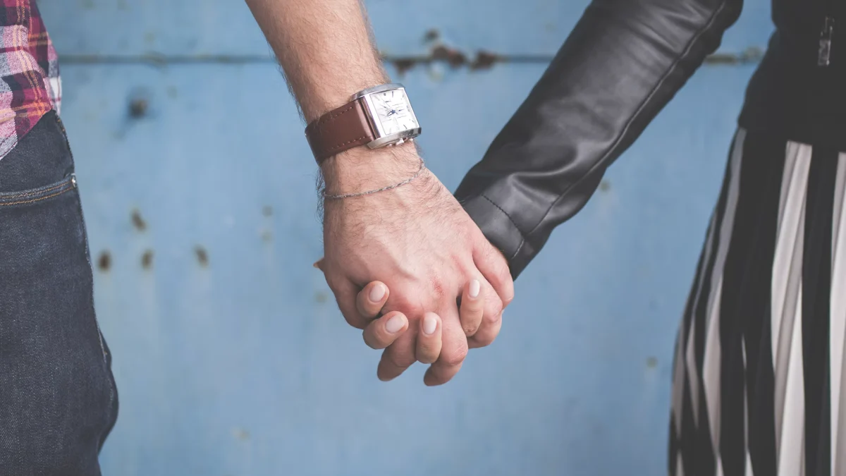 Two people holding hands in front of a blue wall