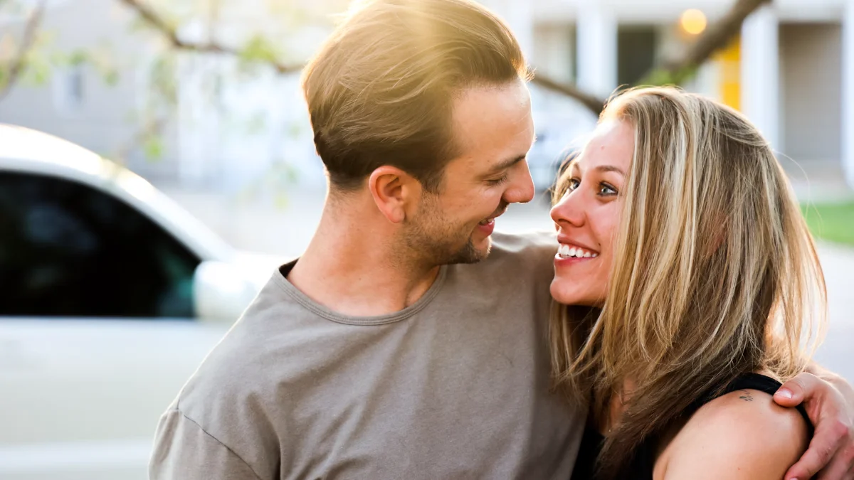 A couple laughing together beside a car