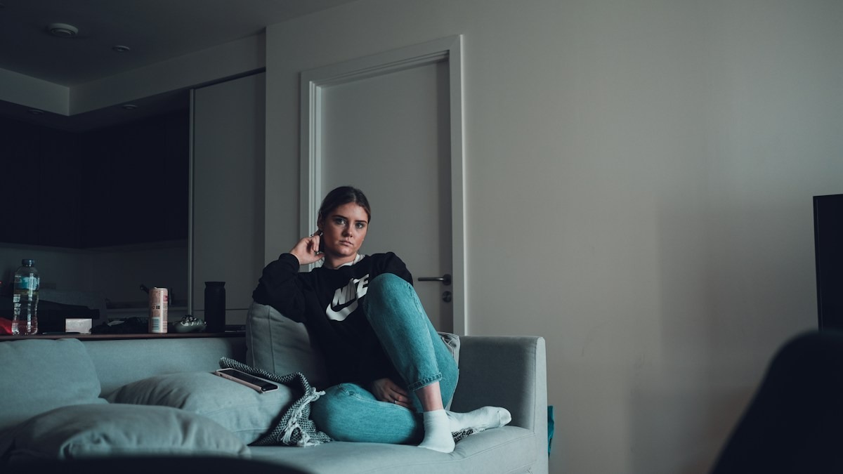 Woman sitting alone on a grey sofa on a quiet evening at home