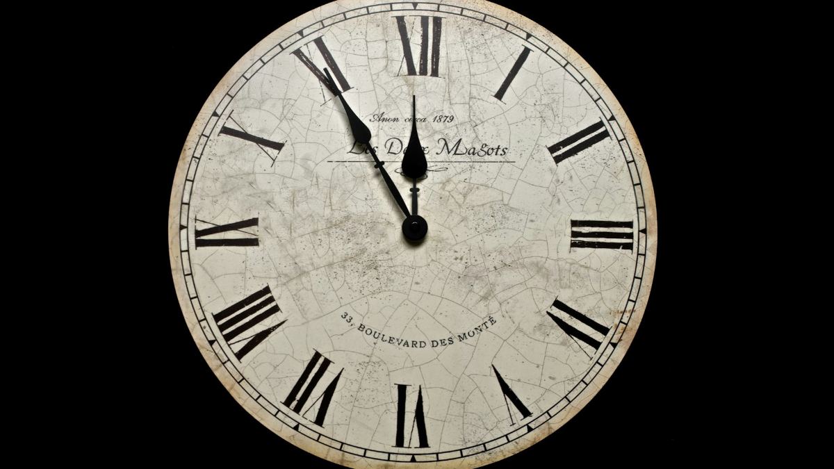 A round clock with Roman numerals against a dark background